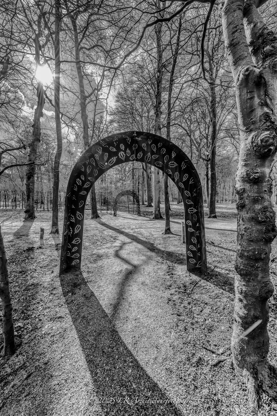 Een stenen boogdoorgang in het Baarnsche Bos, in zwart-wit, met licht aan het einde van de tunnel.