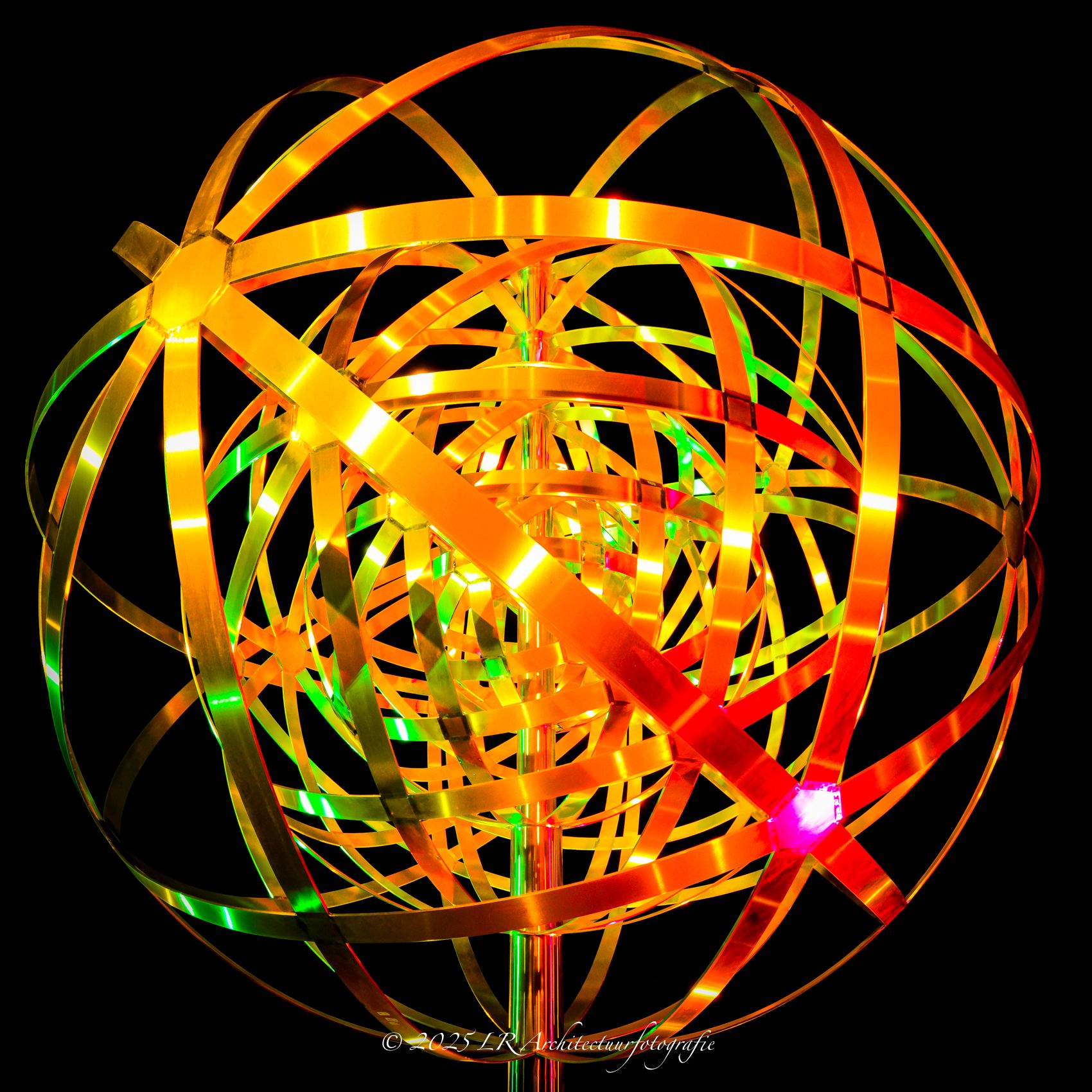 Een bol van gekleurde lichtsporen, gevormd met een lange sluitertijd — een abstracte lichtstudie.
