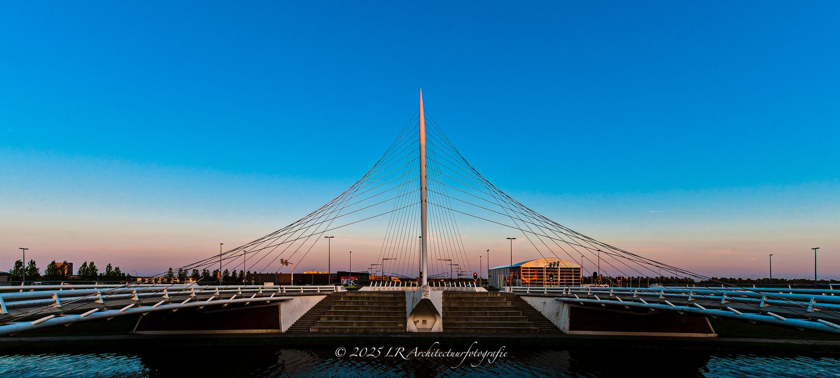 Een panoramische skyline met een verlichte brug in het blauwe uur.
