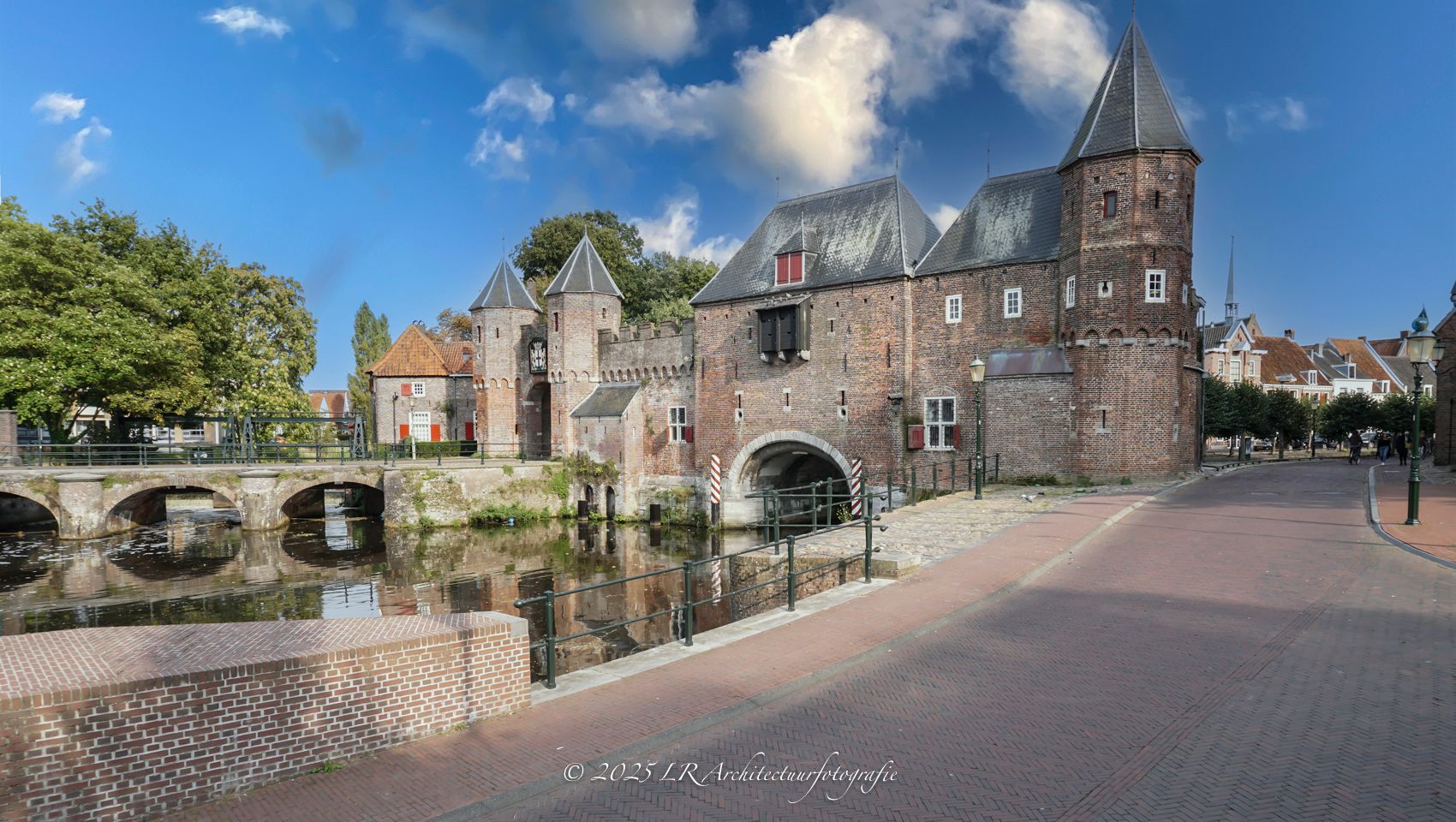 De middeleeuwse Koppelpoort in Amersfoort, weerspiegeld in het water onder een dramatische wolkenlucht.
