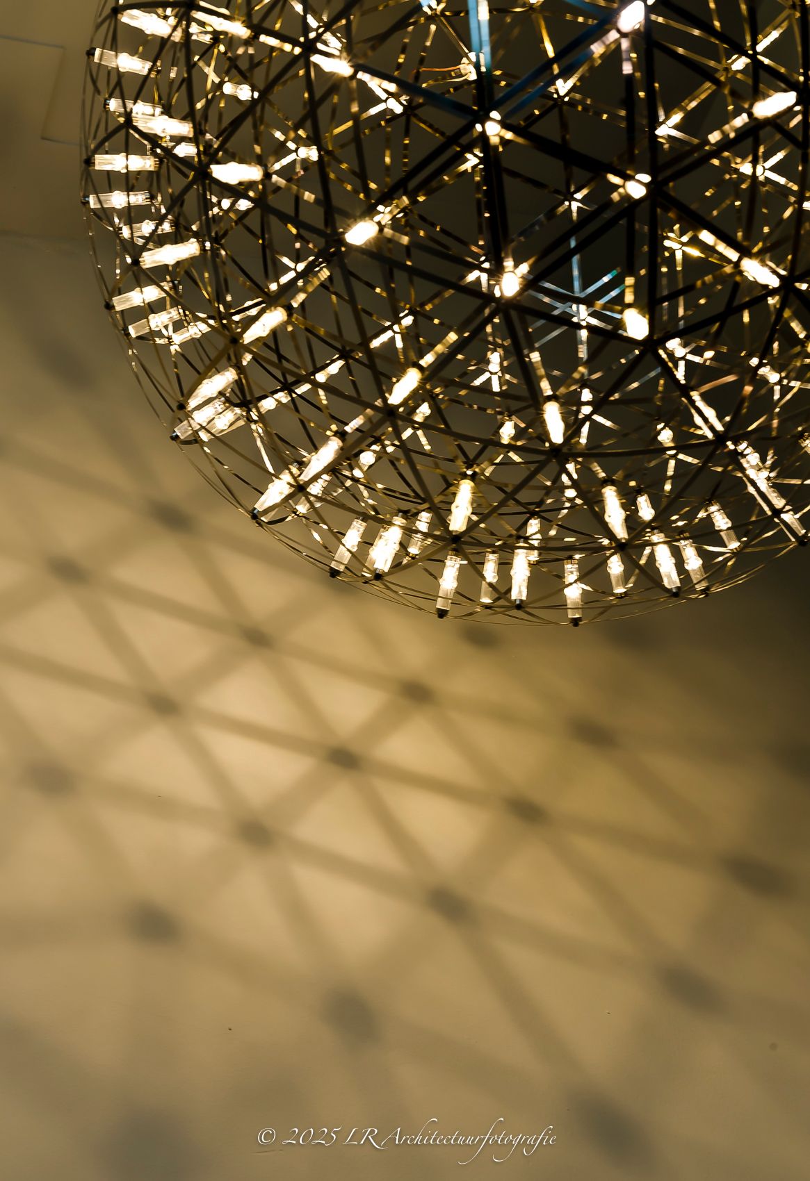 Een cluster verguld ogende lichtarmaturen dat warm oplicht tegen een donkere achtergrond.