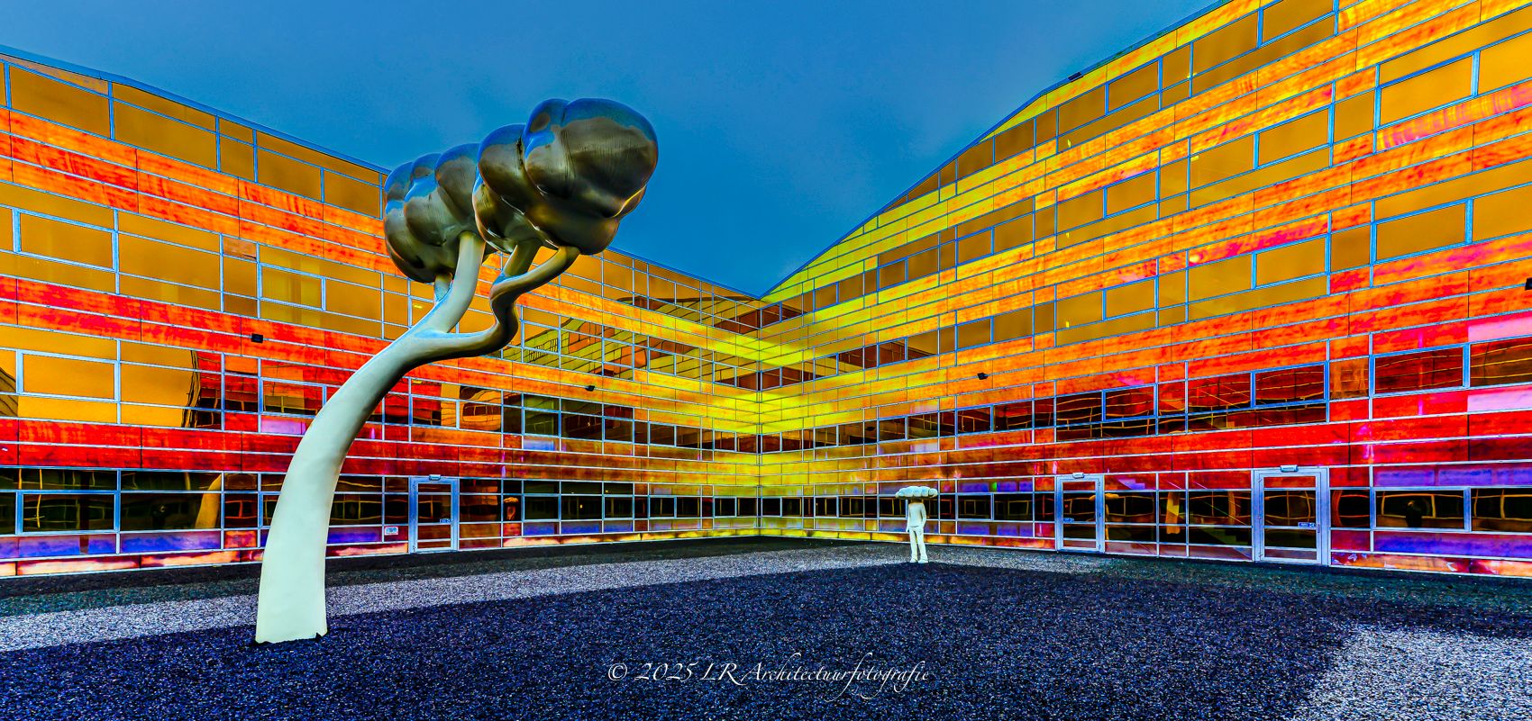 Een kleurrijke glasgevel waarin gekleurde panelen een abstract patroon vormen.