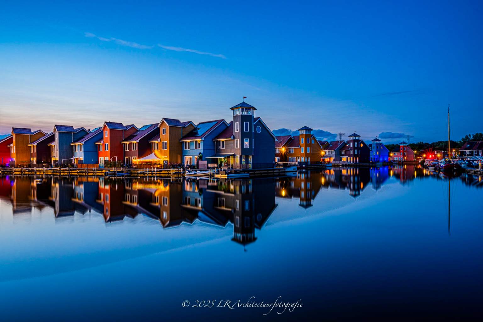 De Reitdiephaven in Groningen tijdens het blauwe uur, kleurrijke houten woningen weerspiegeld in stil water.