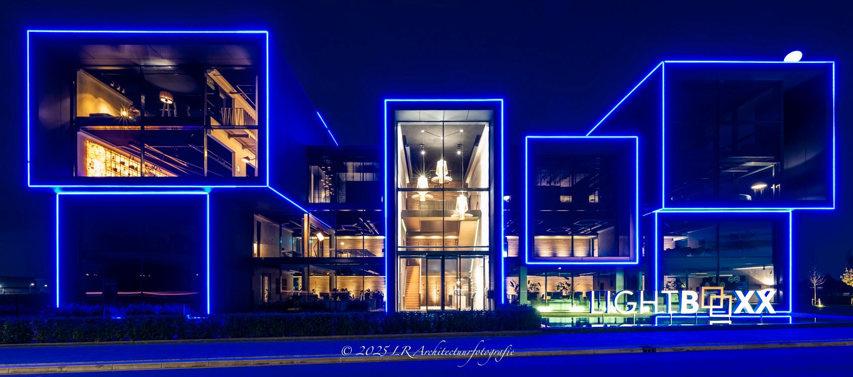 Een breed nachtbeeld waarin een gebouw baadt in blauw en wit licht.