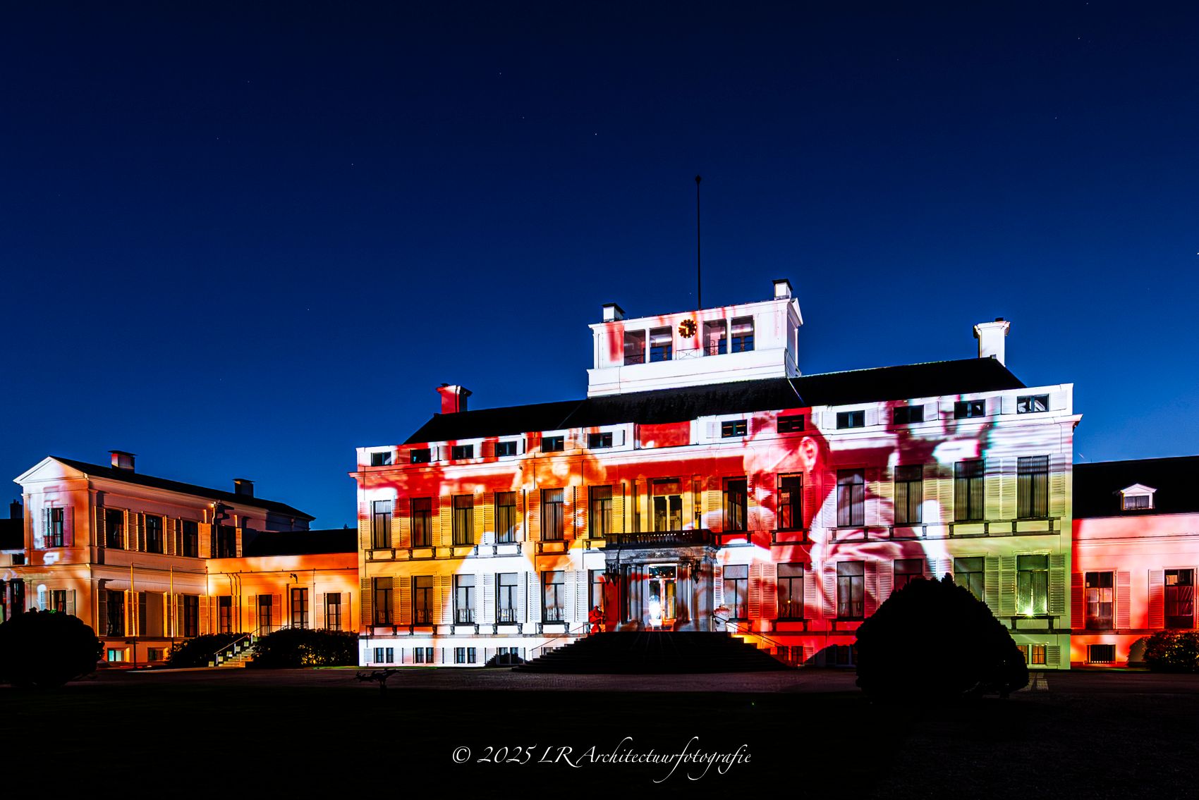 Paleis Soestdijk 's avonds, overgoten met een kleurrijke lichtprojectie.