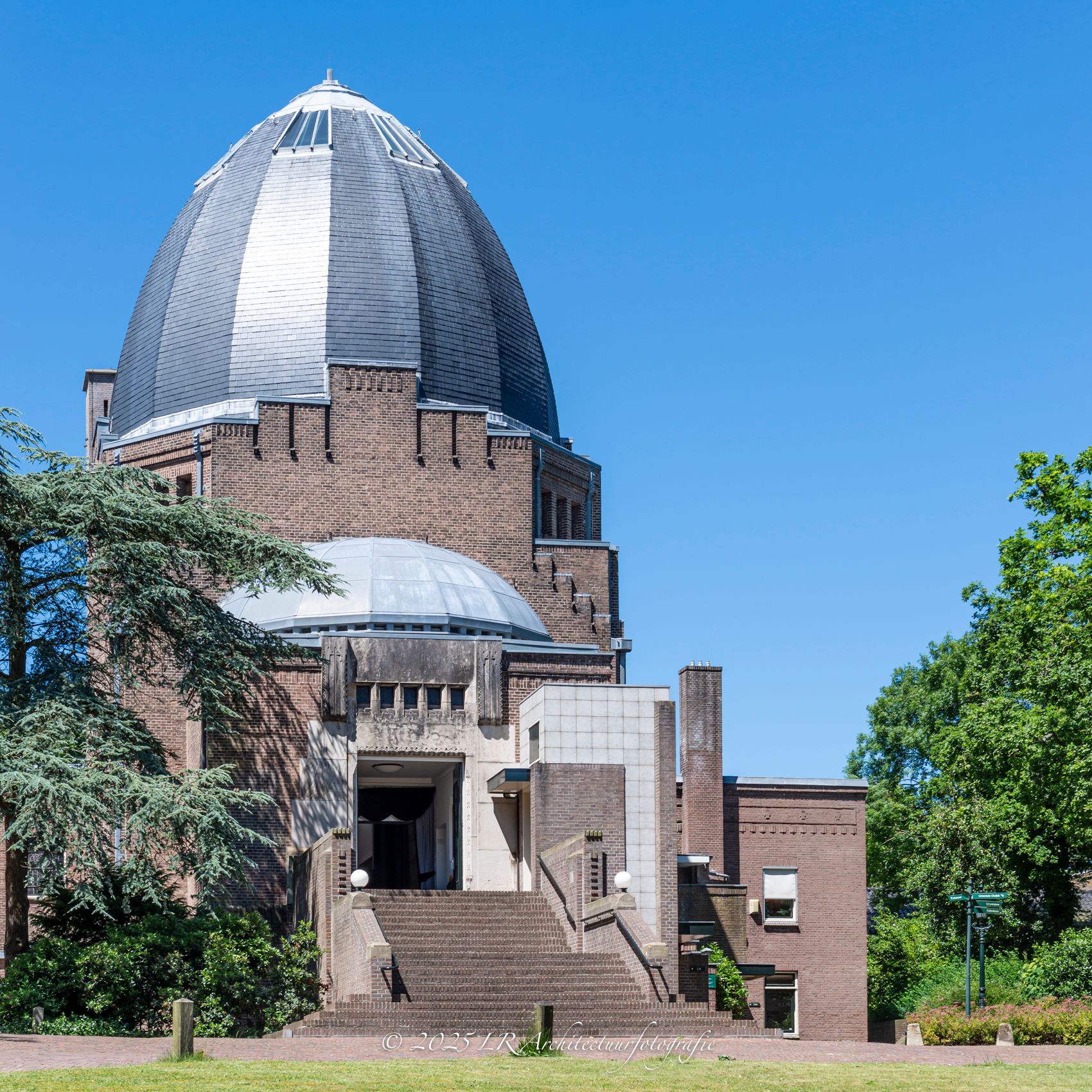 Een geometrische glazen koepel van crematorium Westerveld, van binnenuit gezien tegen de lucht.