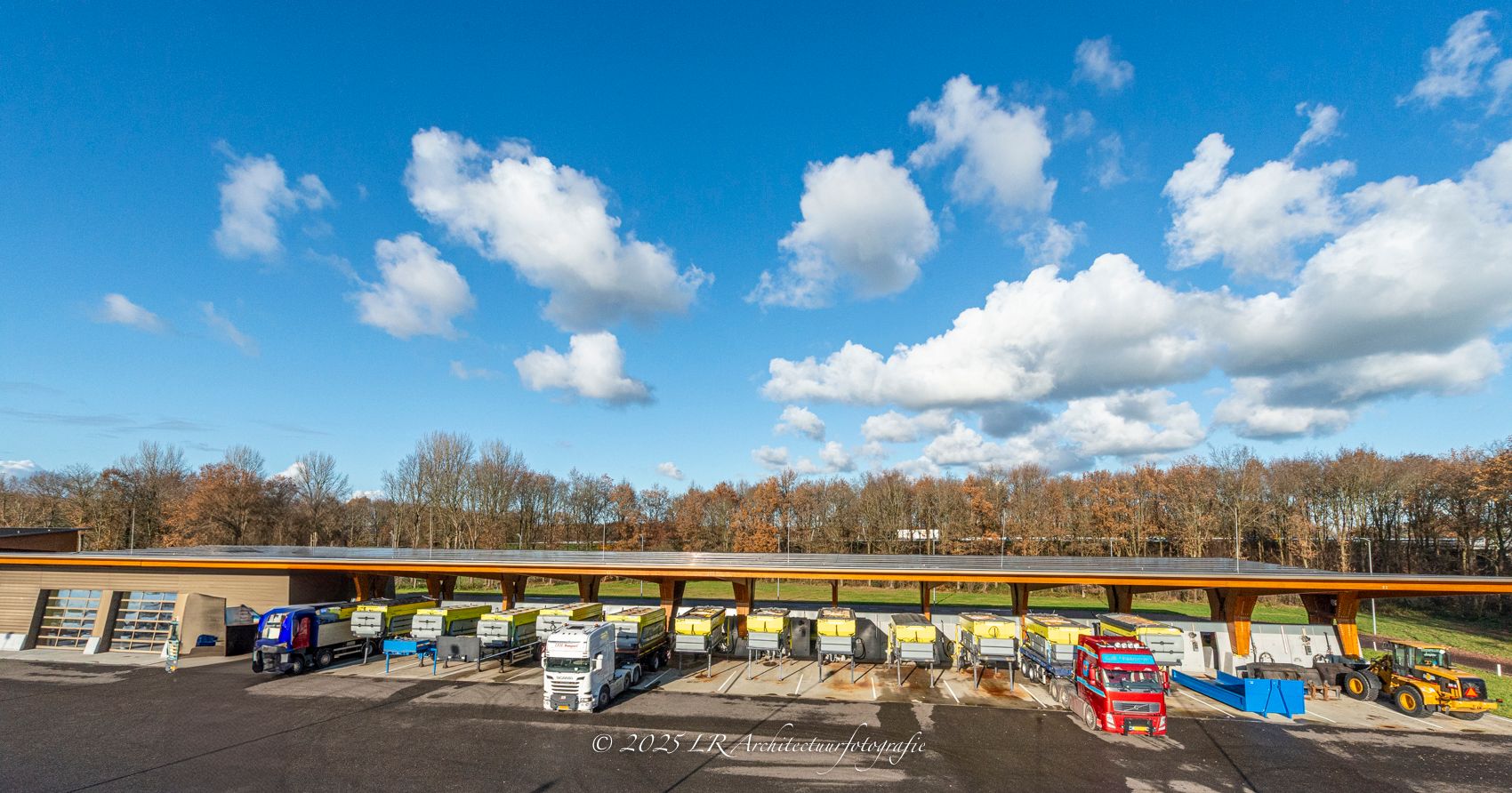 Een luchtopname van een uitgestrekt veld met zonnepanelen op een industrieel terrein.